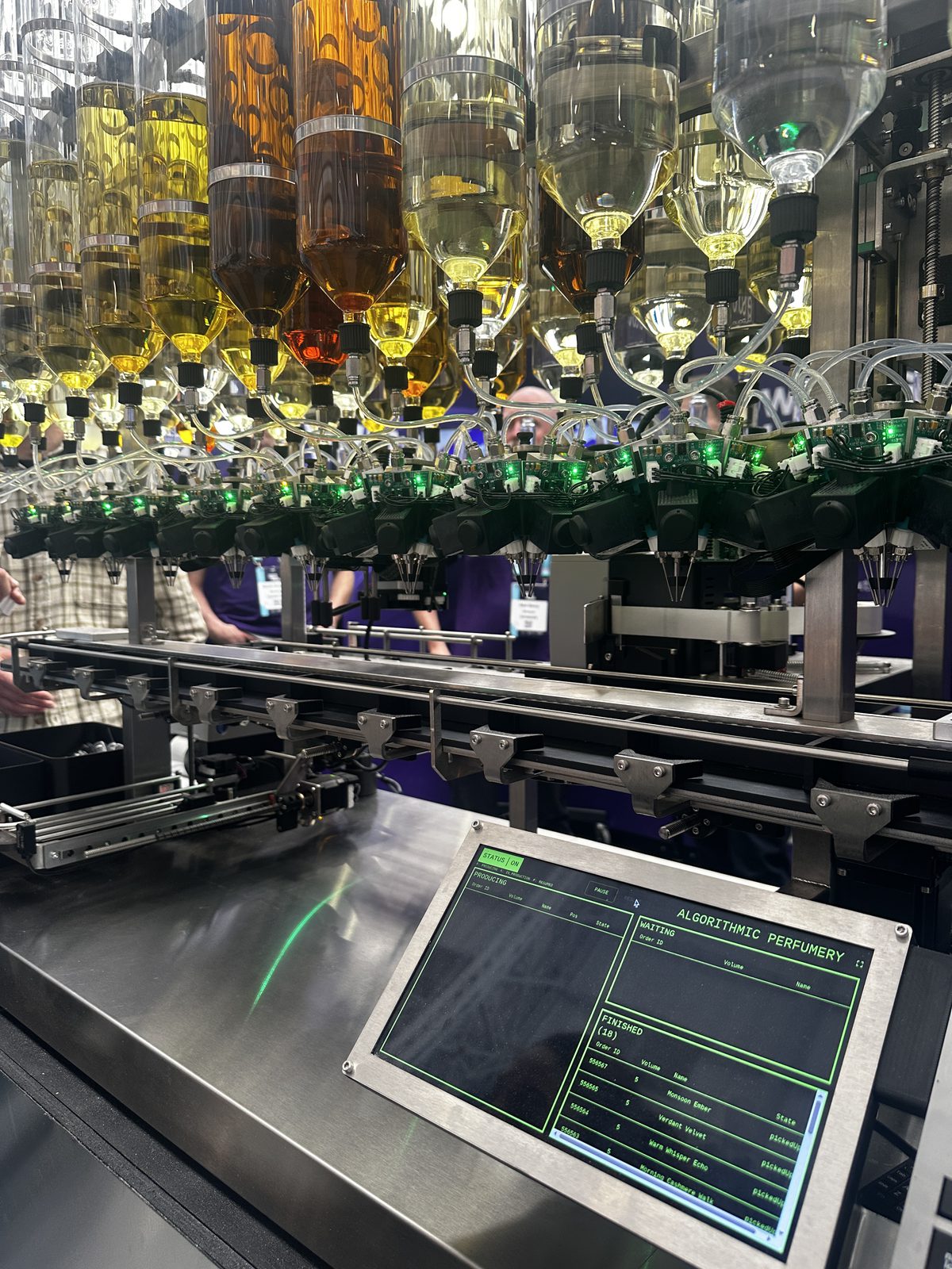 Ensono's algorithmic perfumery machine, rows of coloured scent bottles beside a status screen