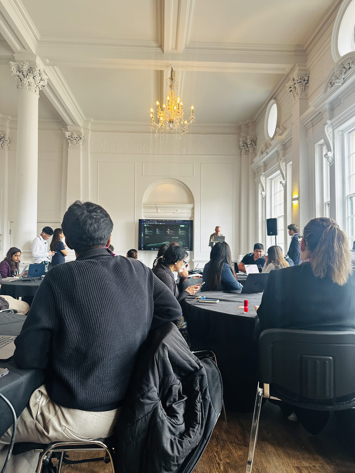 Inside the Lovable hackathon room, people building at laptops under a chandelier
